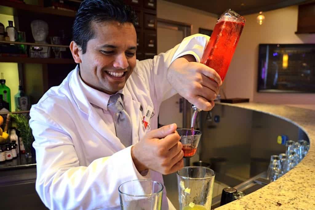 Carnival bartender mixing cocktails at the Alchemy Bar.