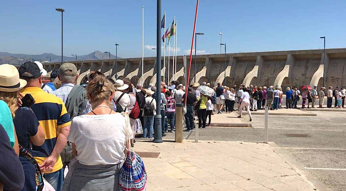 Hundreds of cruise passengers wait in line to enter the terminal.