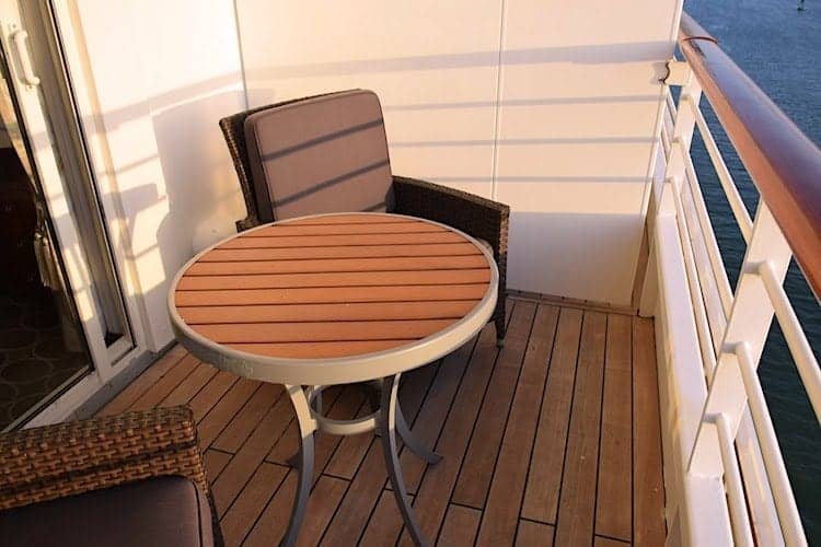 Crystal Serenity stateroom balcony with two chairs and a small table.