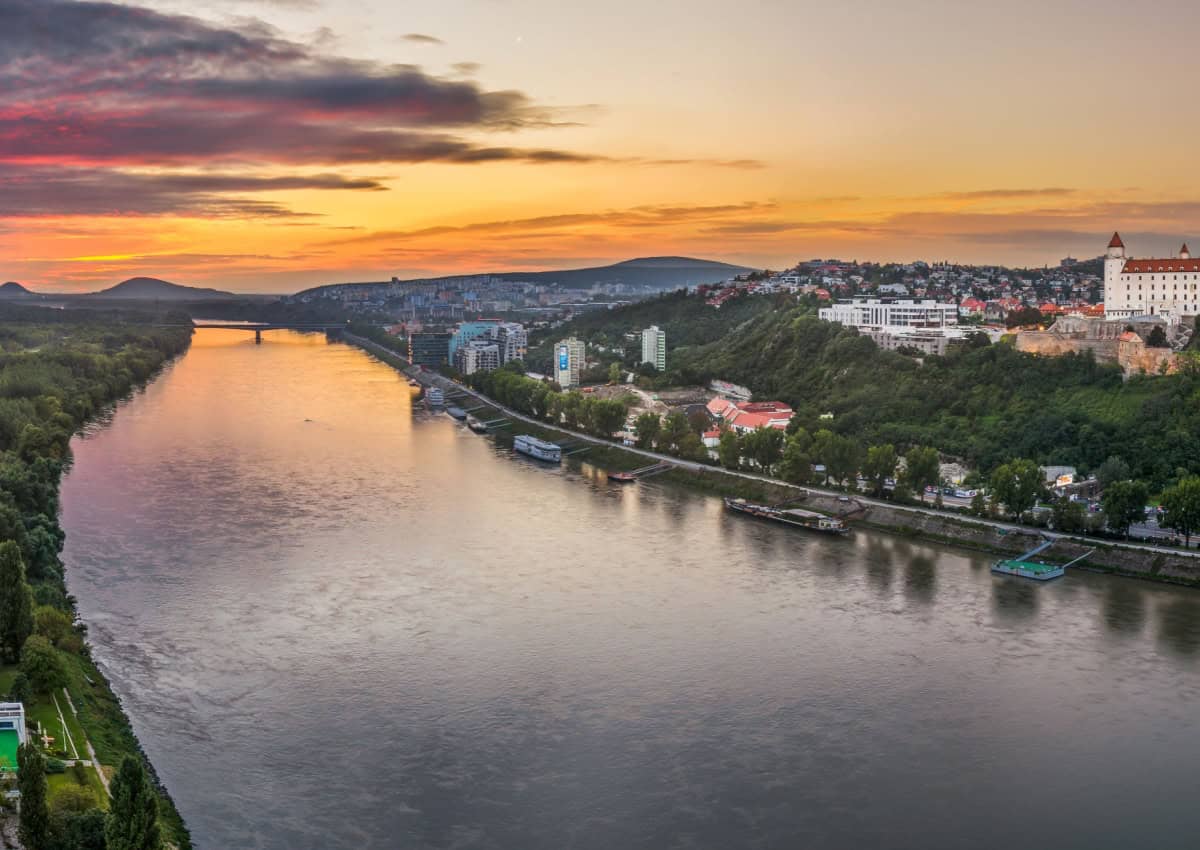 Danube river with castle in background at sunset.