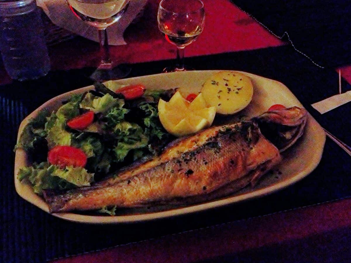 Portuguese whole fish on a dinner plate with salad and lemon.