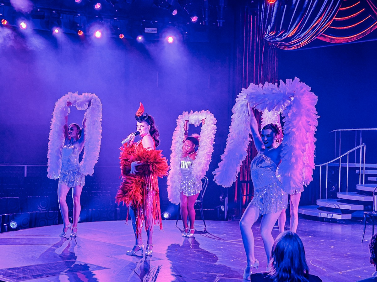 Performers on stage aboard Holland America Nieuw Statendam with feather boas.