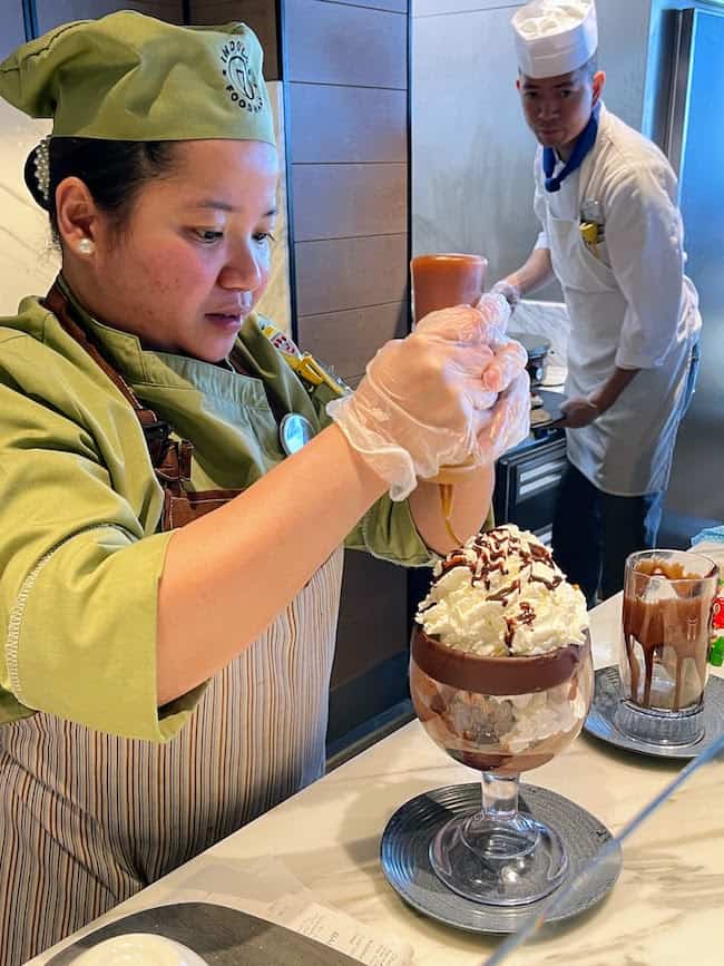 Indulge Food Hall with server making a hot fudge sundae. 