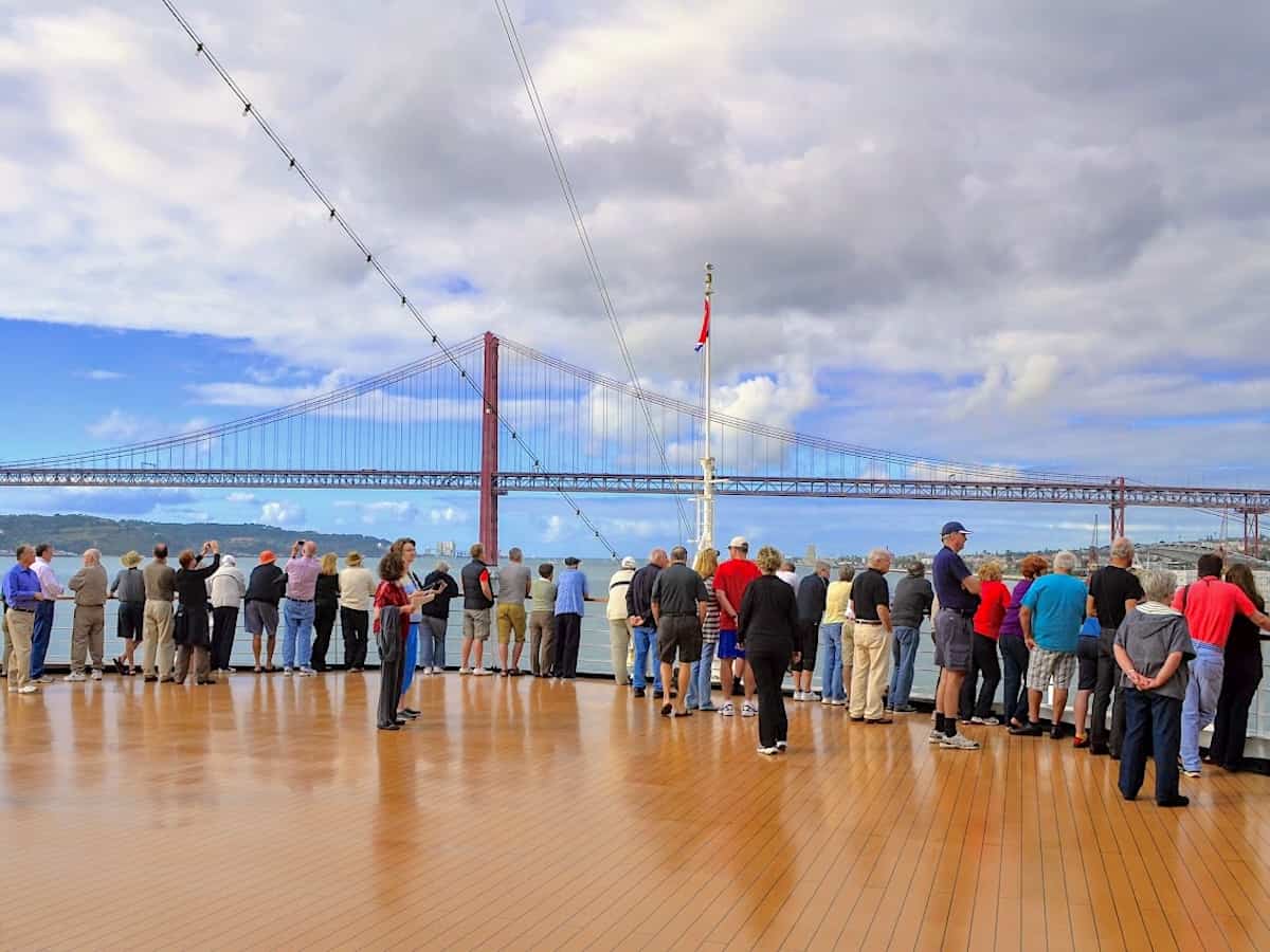 Passengers at the bow of the ship near the bridge at Lisbon harbor. 