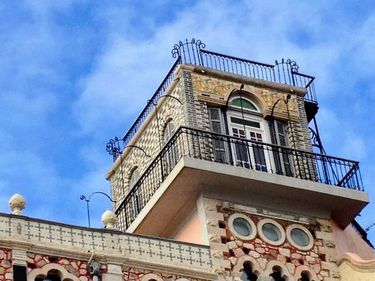 Intricate iron decorations are a guard rail at the top of an apartment building.