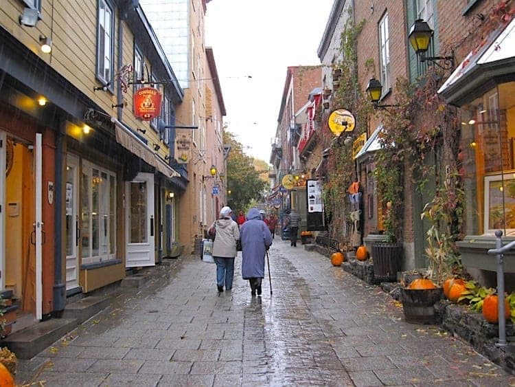 Two women in raincoats strolling through Old Quebec. 